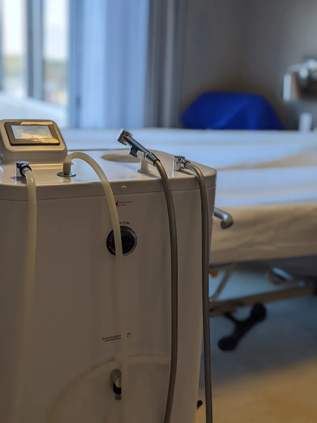 The Wishower beside a patient bed, ready for an in-bed shower