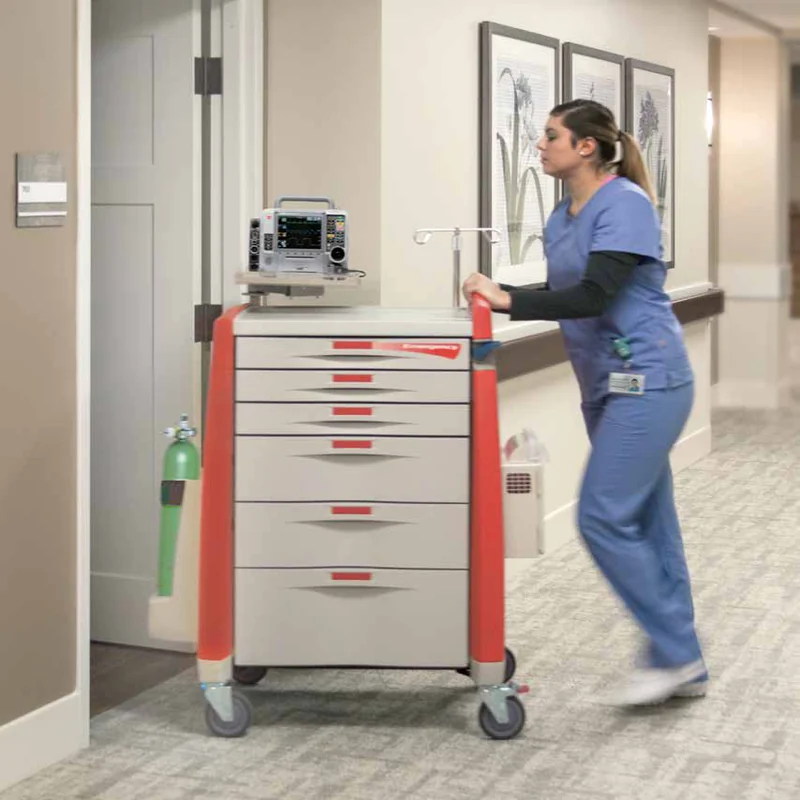 A nurse pushes a red Avalo emergency cart with a defibrillator down a corridor
