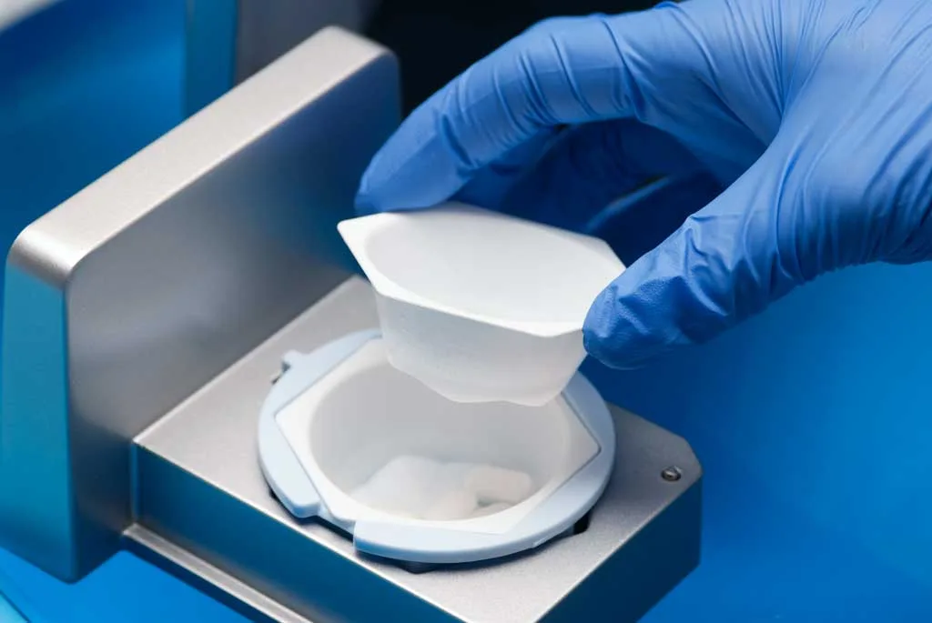 A gloved hand placing the second cup in the SafeCrush drawer